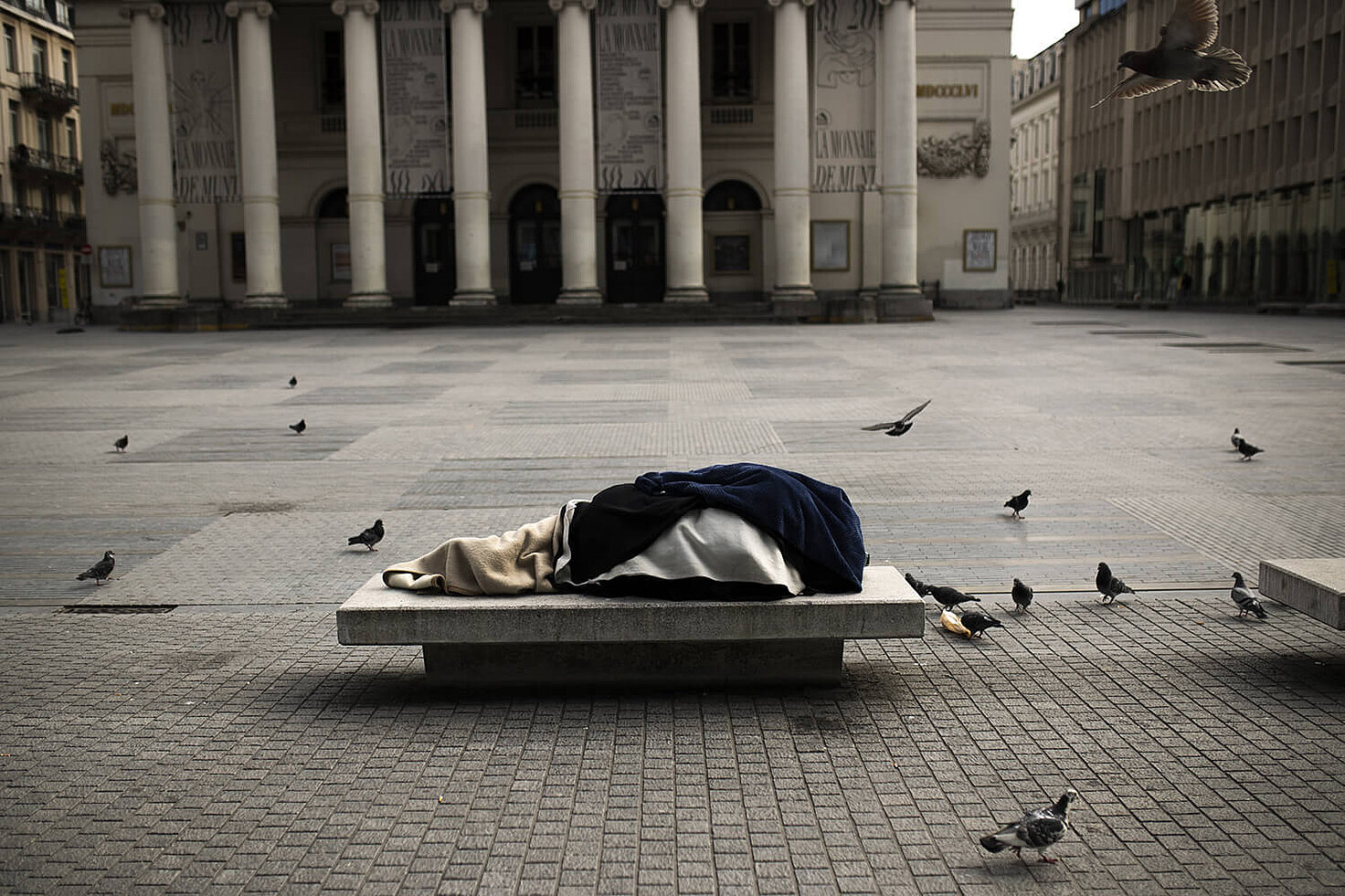 Una persona sin hogar duerme en un banco en la plaza de La Monnaie en Bruselas, el viernes 3 de abril de 2020