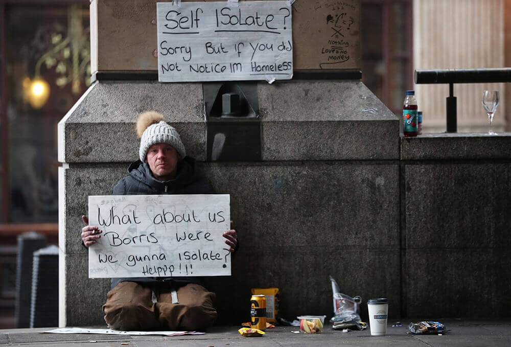 Un hombre sin hogar sostiene un cartel en el exterior de la estación del metro de Westminster mientras continúa la propagación del COVID-19, en...