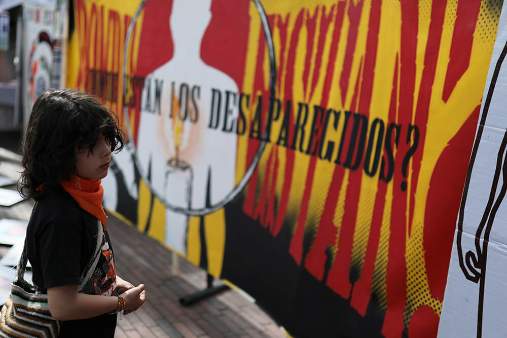 Un muchacho se para frente a un letrero que pone: "¿Dónde están los desaparecidos?" el Día Internacional de las Víctimas de Desapariciones...