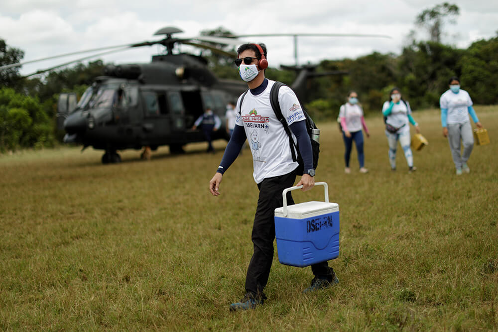 Un profesional de la salud carga con cajas de vacunas contra la COVID-19 mientras llegan a la aldea indígena de Taracua Igarape, durante un...